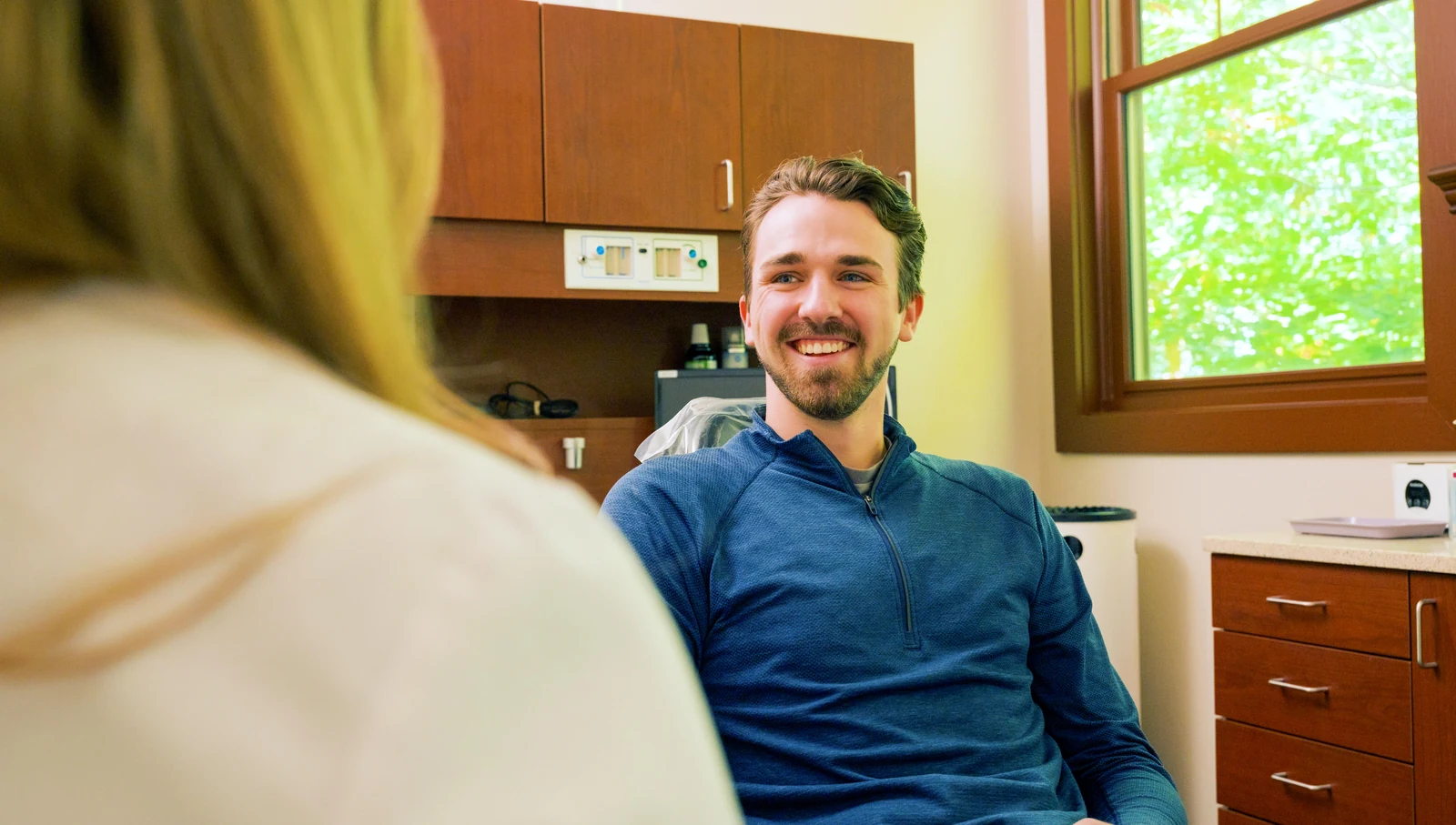A relaxed, smiling patient talking with the dentist