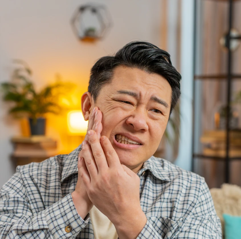 A man holding his jaw in discomfort