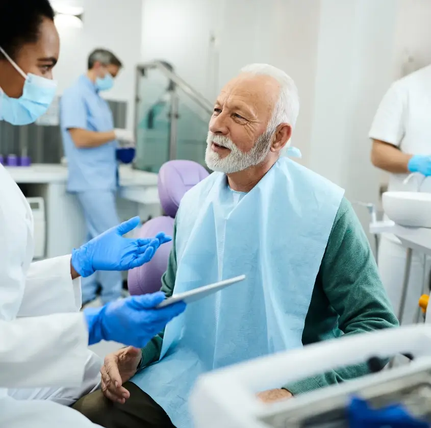 An older patient discussing his treatment plan with the dental team