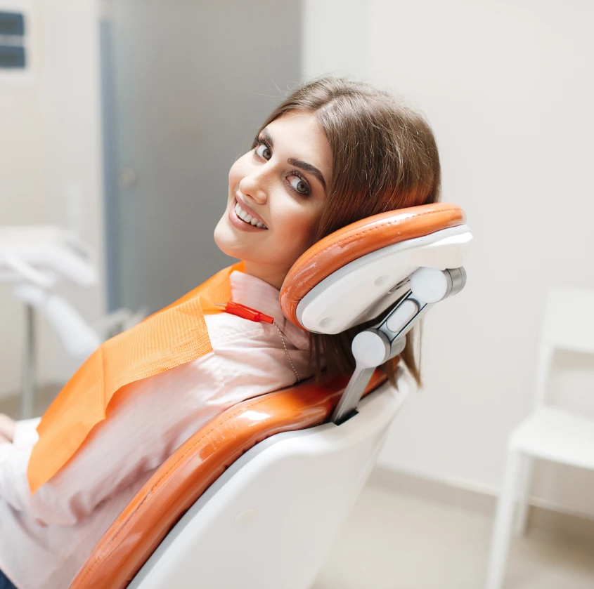 A smiling patient reclined in the treatment chair before her cleaning