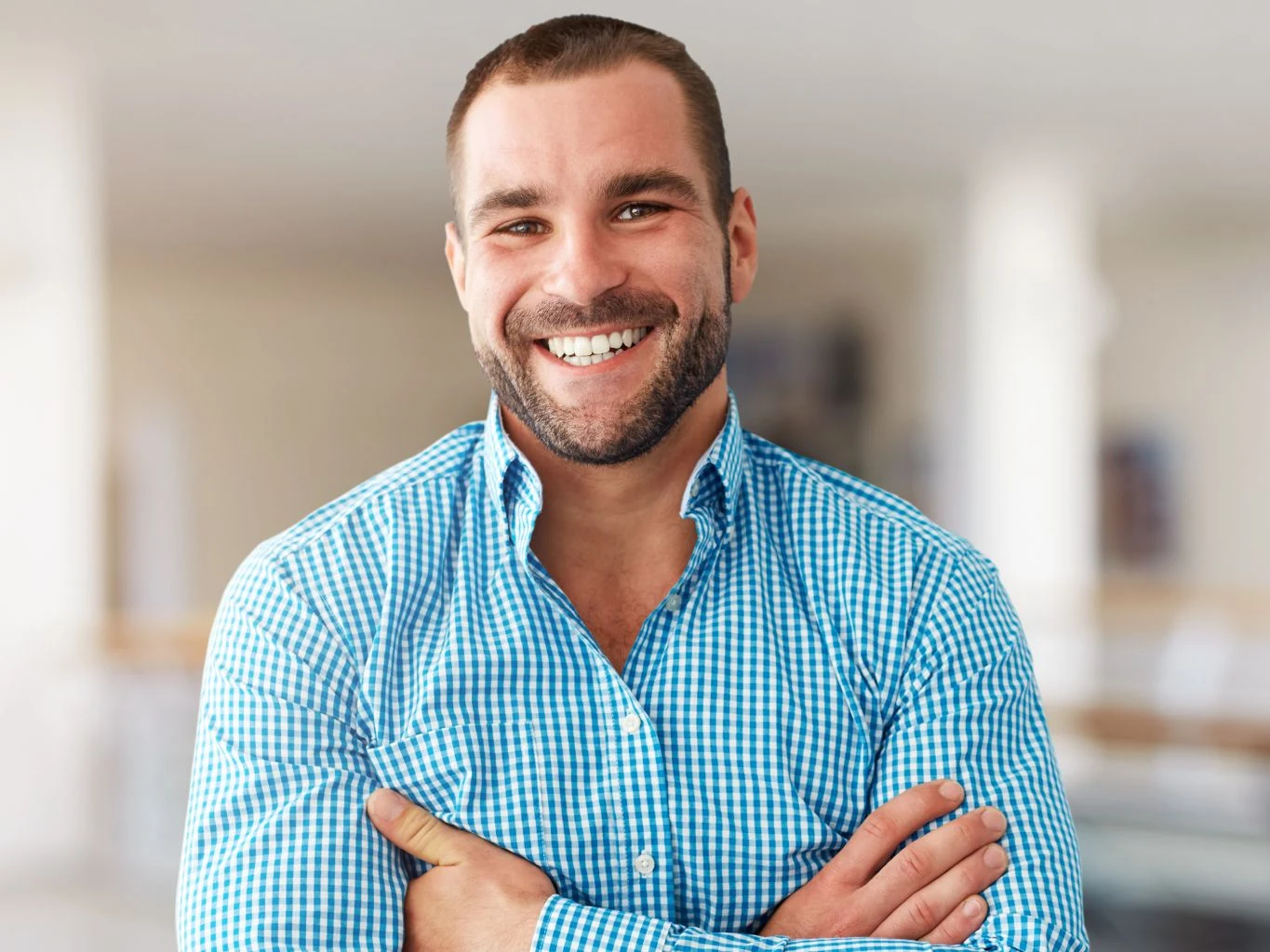 A smiling man with arms crossed, confident in his smile